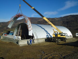 Una grúa ayuda a la construcción de una estructura arqueada de acero.