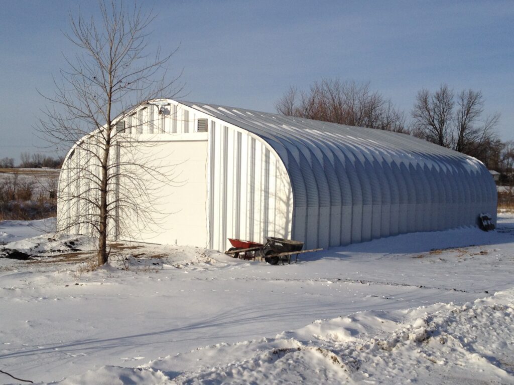 Una estructura del Modelo A SteelMaster bajo un cargo de nieve en Minnesota. La estructura es un garaje, hay un arból sin hojas (en medio del invierno).