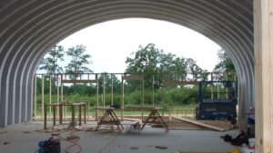Una estructura arqueada de acero en construcción. Es el modelo Q SteelMaster. Hay andamios debajo de la estructura.